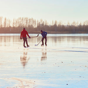 Blog banner image of two men playing hockey on a frozen lake.