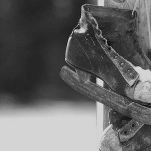Image of old hockey skates near an ice covered pond.